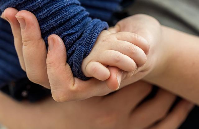 Bild mit Kinderhand und einer Erwachsenenhand, verbindend